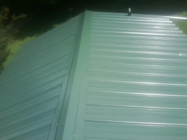 New green metal panels meeting at the ridge of a roof — Flat Roof Repair work by our crew in Valley Park