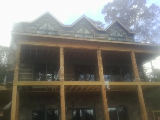 Dormers and porch framing on a large log home under construction — Roof Coating work by our crew in Valley Park