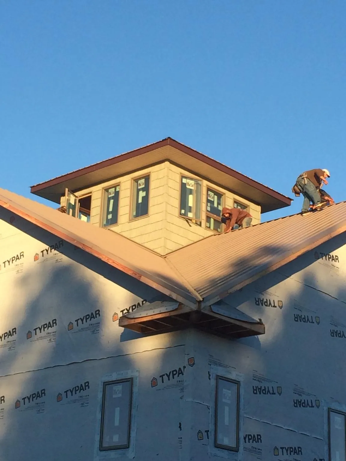 Roofers working around a rooftop cupola on a new metal roof at sunset — Roof Waterproofing in Valley Park by Roofing Brothers